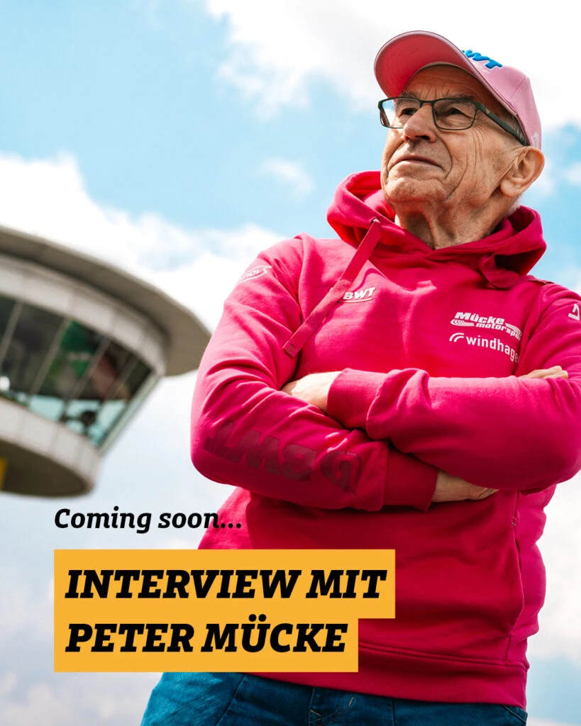 Peter Mücke in pinkem Mücke Motorsport Hoodie und Cap mit verschränkten Armen vor dem Sachsenring-Turm und der Aufschrift „Coming soon... Interview mit Peter Mücke."