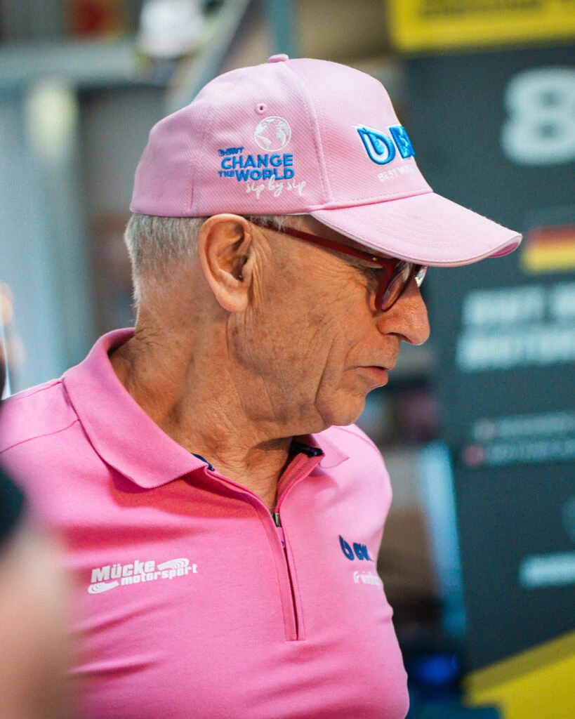 Nahaufnahme von Peter Mücke mit rosa BWT-Kappe und Brille beim Mücke Motorsport Interview in Berlin